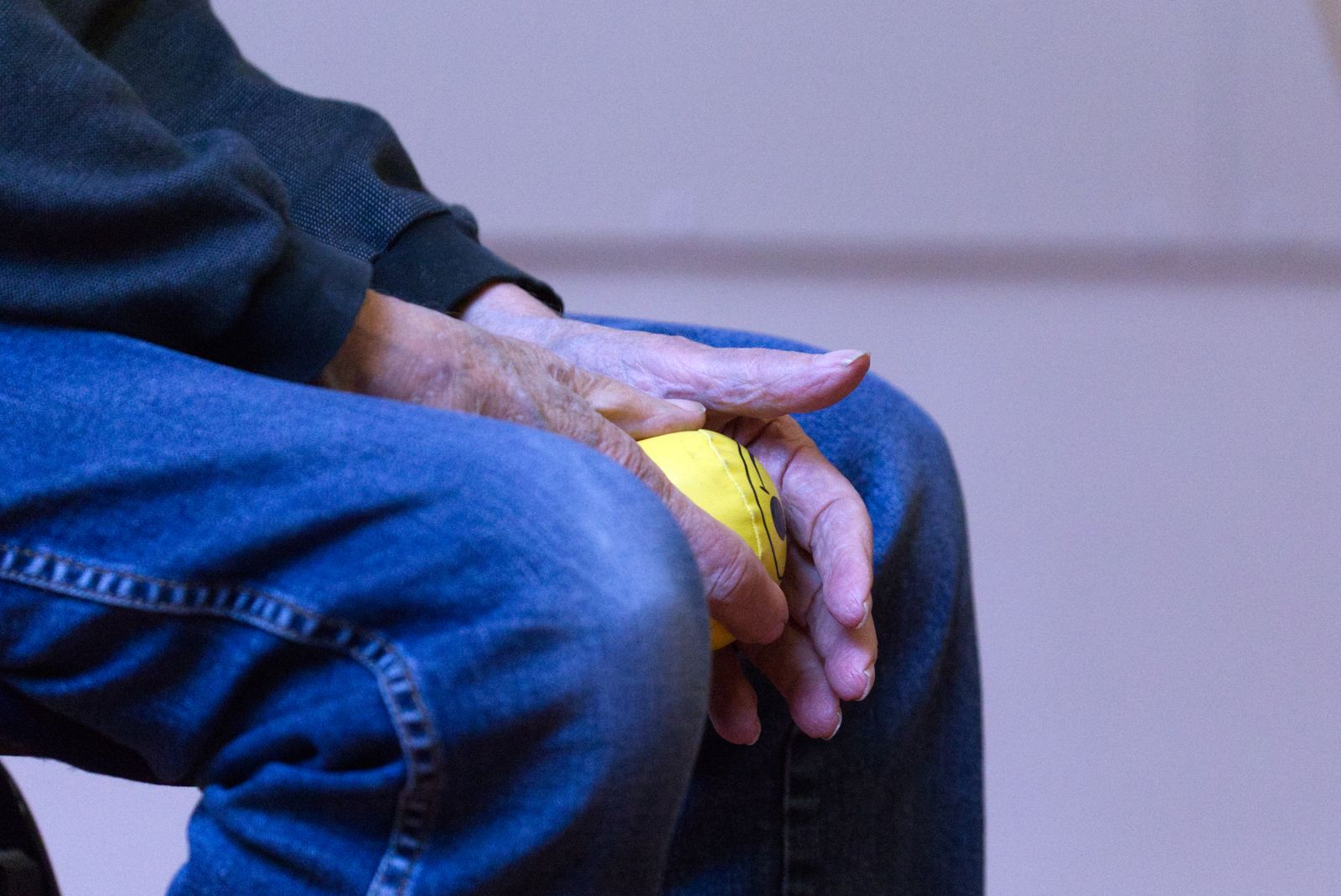 Older person working stiff, arthritic hands with a therapy ball
