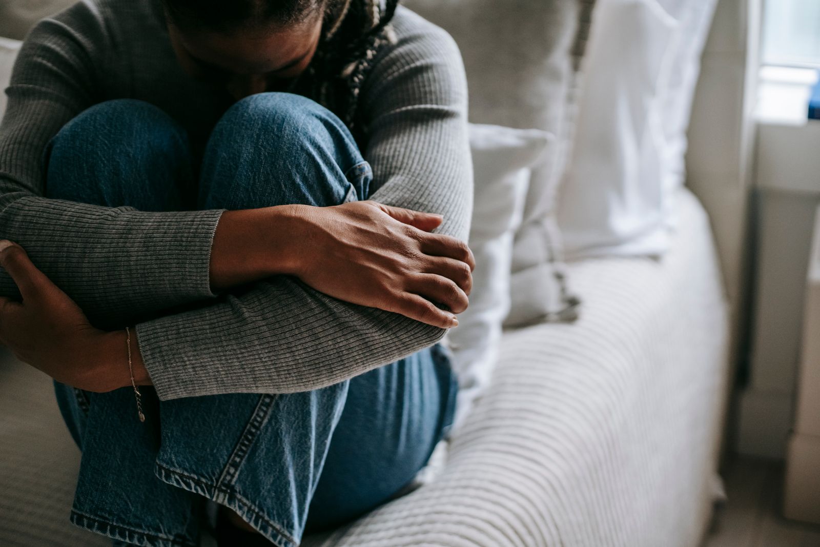 Person sitting on the edge of a bed hugging their knees during a flare of pain