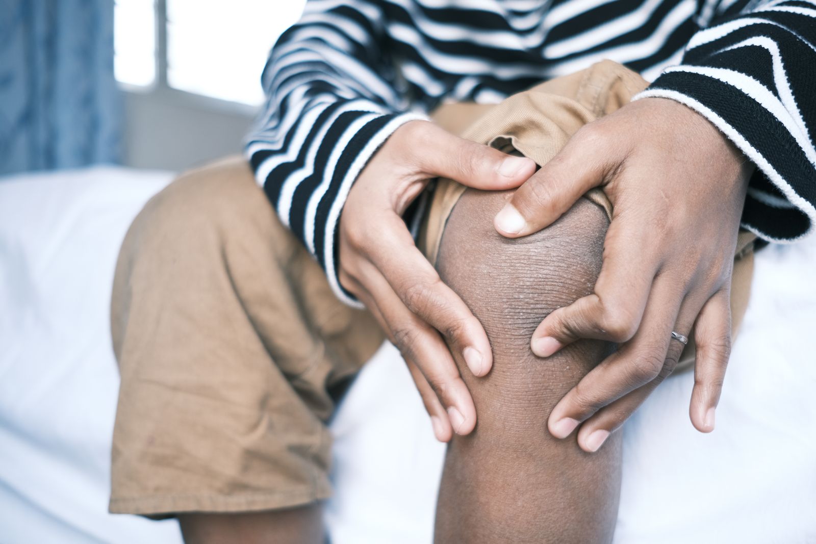 Person holding the inner side of a painful knee