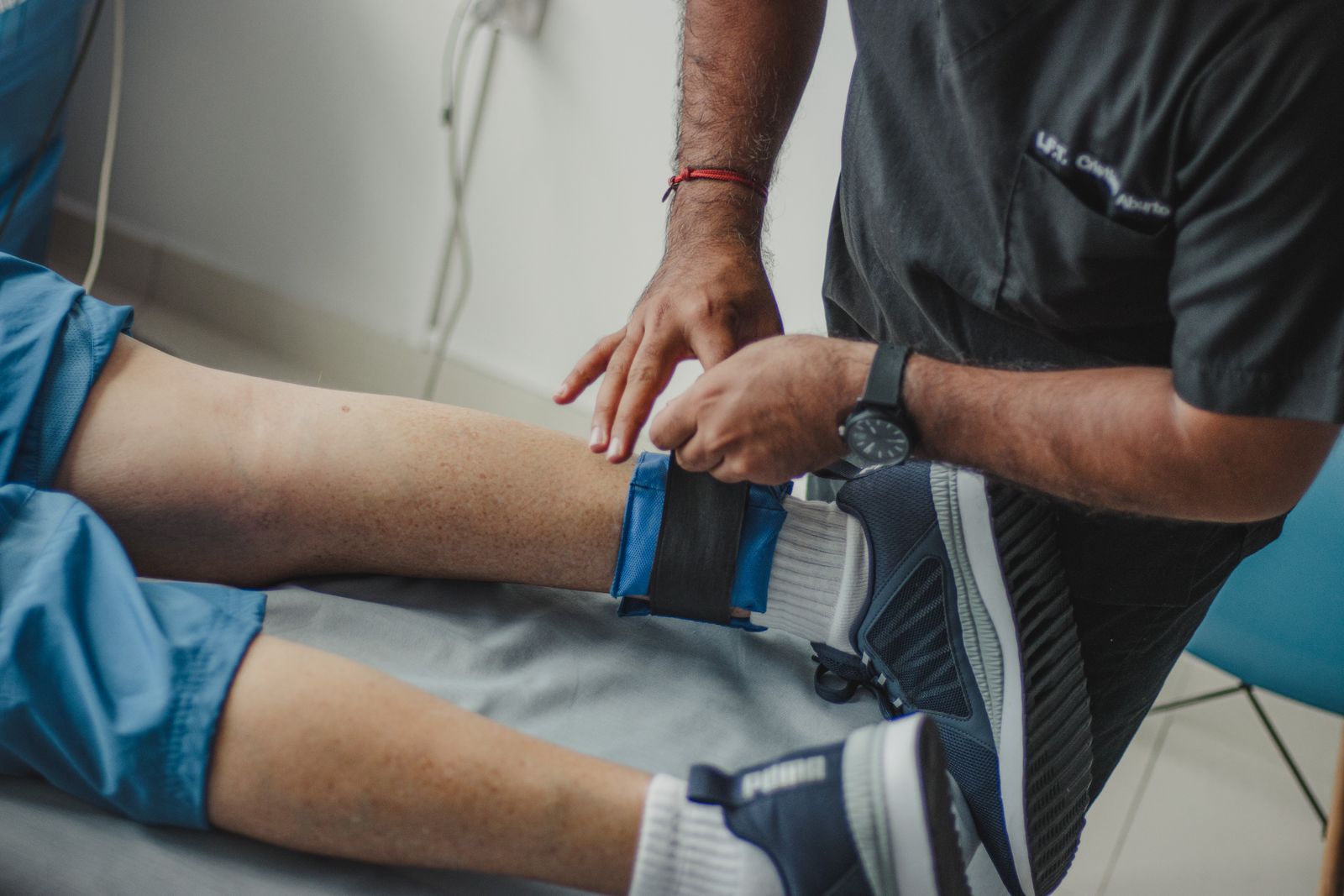 Clinician fitting an ankle weight to a patient's leg during post-operative rehab