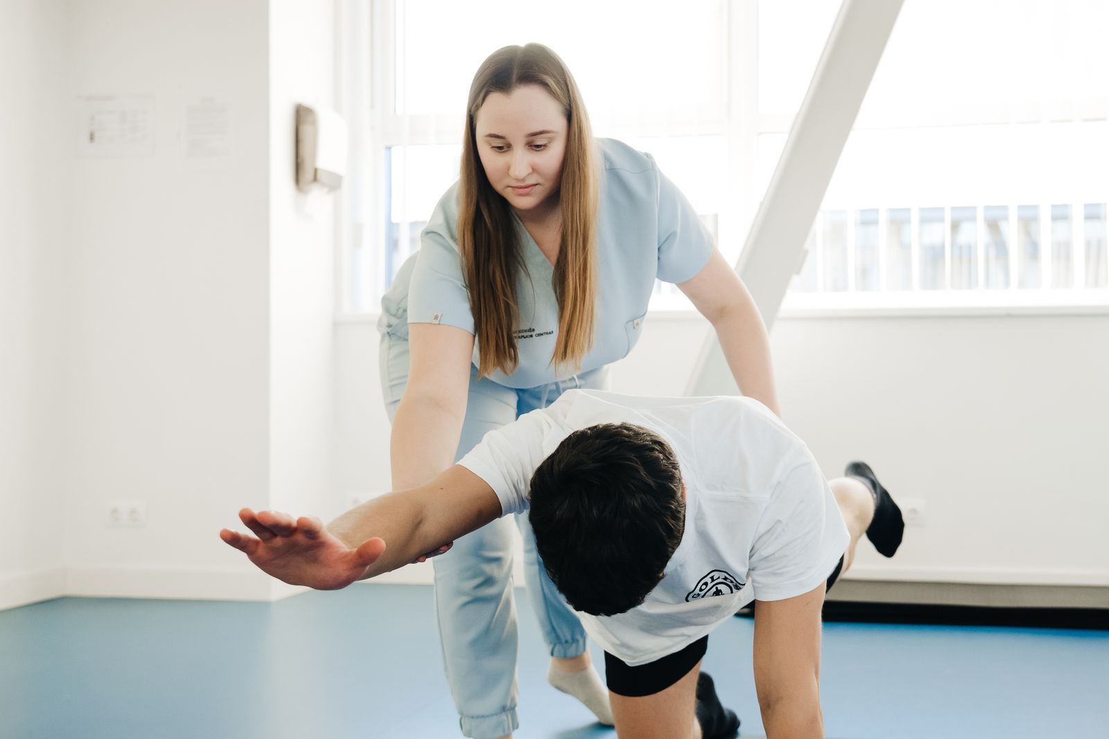 Therapist supporting a patient through a balance and reaching exercise