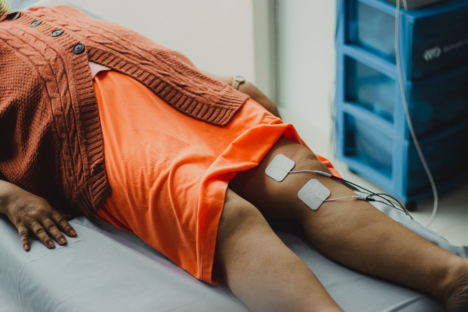 TENS electrode pads attached to a person's leg with lead wires running to the unit