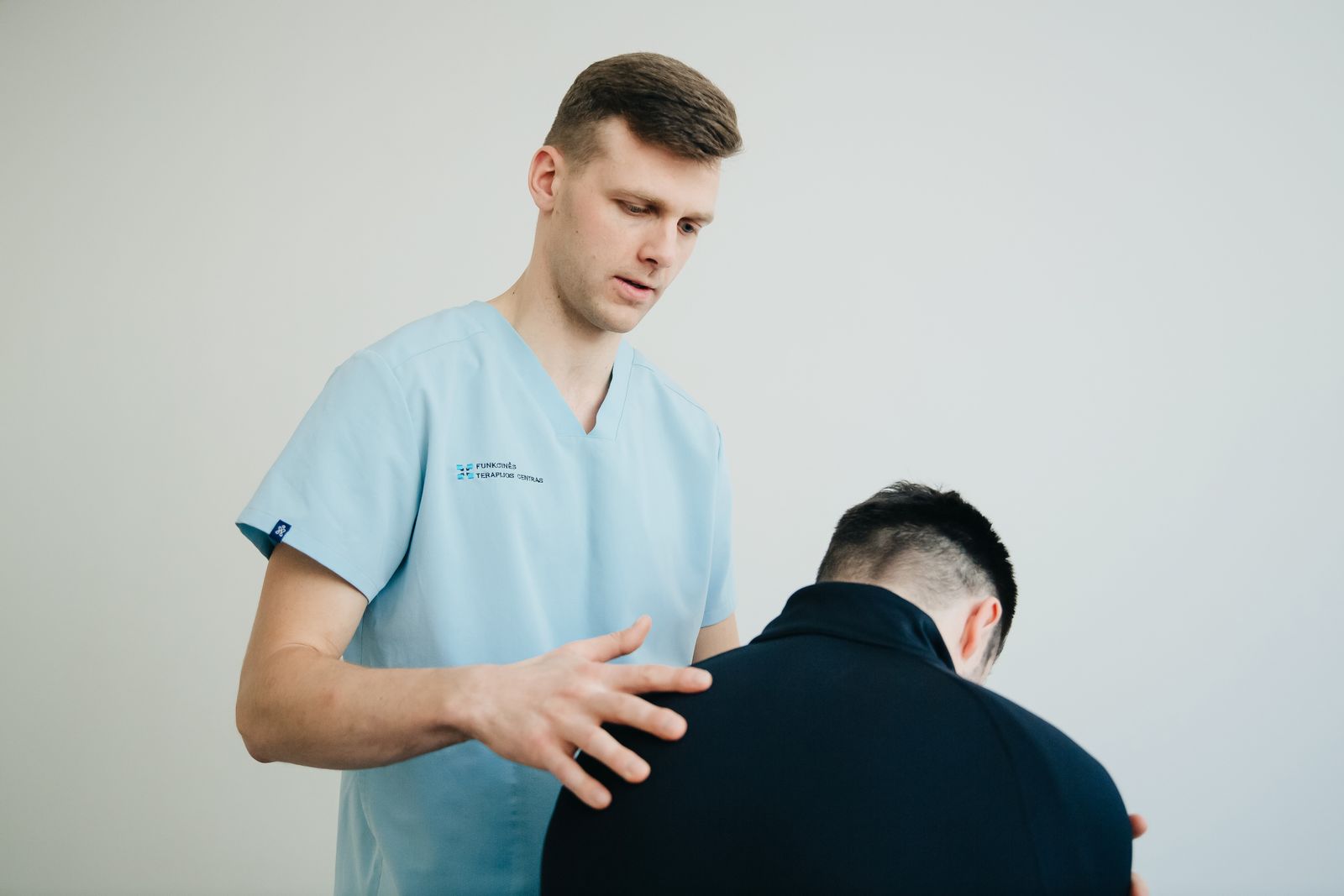 Physiotherapist in scrubs explaining a treatment plan to a patient