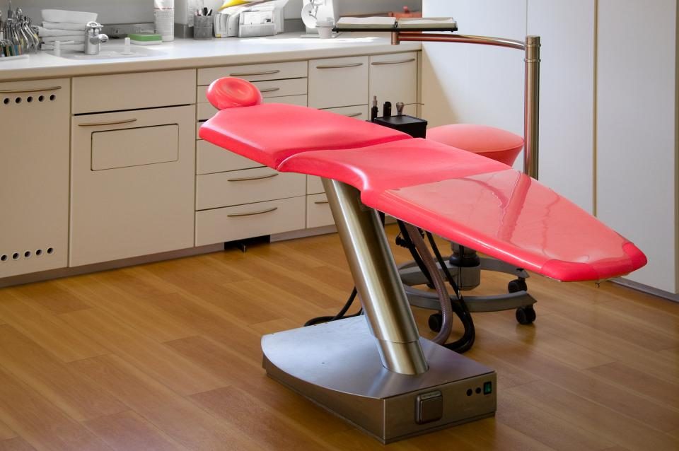 A treatment couch in a clinic room with equipment on the worktop behind