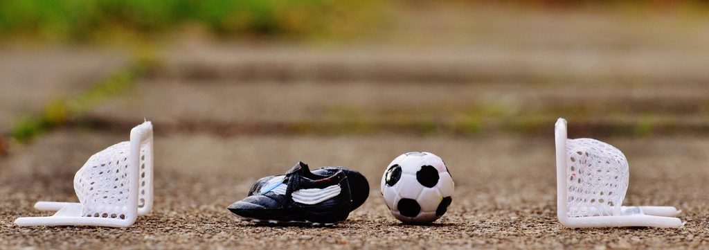 Football boots, a ball and shin pads set out on grass