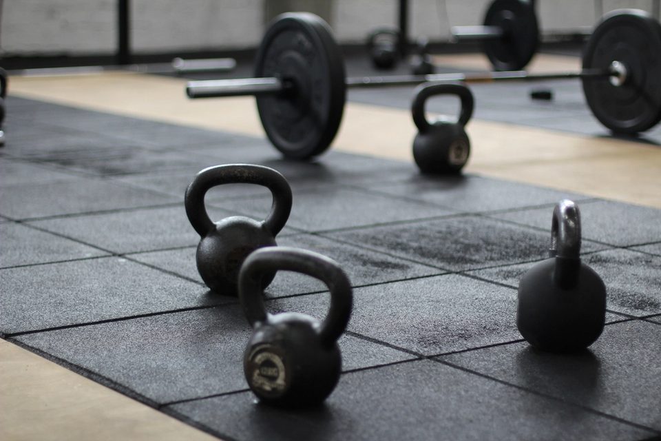 Kettlebells and loaded barbells on a gym floor