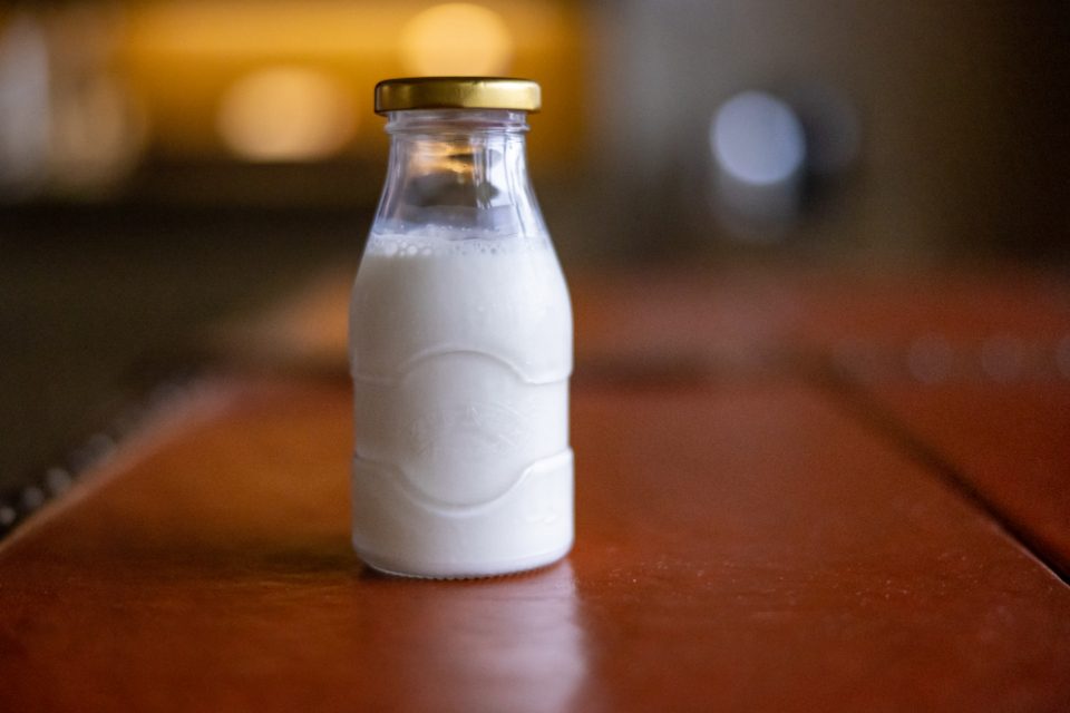 A small glass bottle of milk standing on a wooden table
