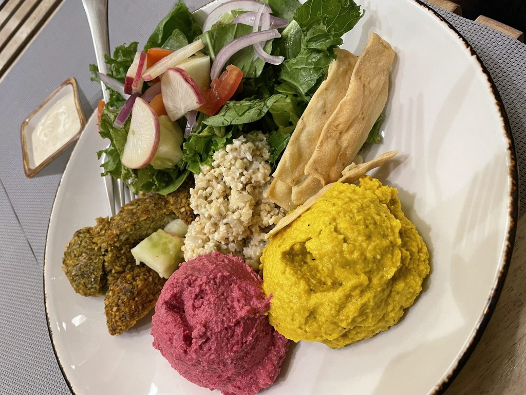 A plate of salad, hummus, falafel and grains