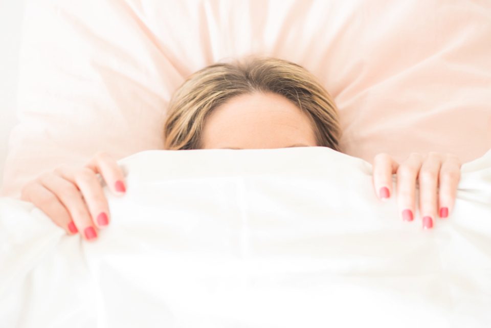 A woman asleep in bed with the duvet pulled up