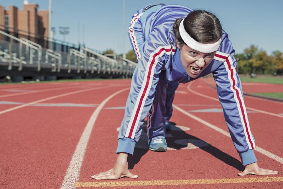A sprinter set in the start position on an athletics track