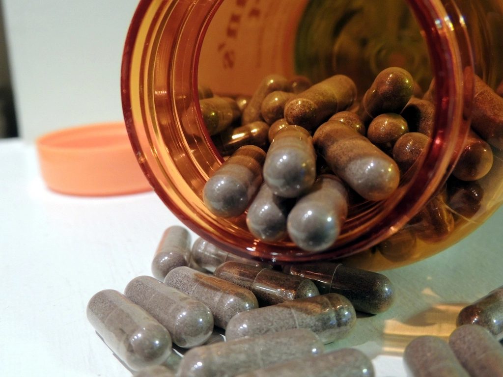 Capsules spilling from an open supplement bottle onto a table