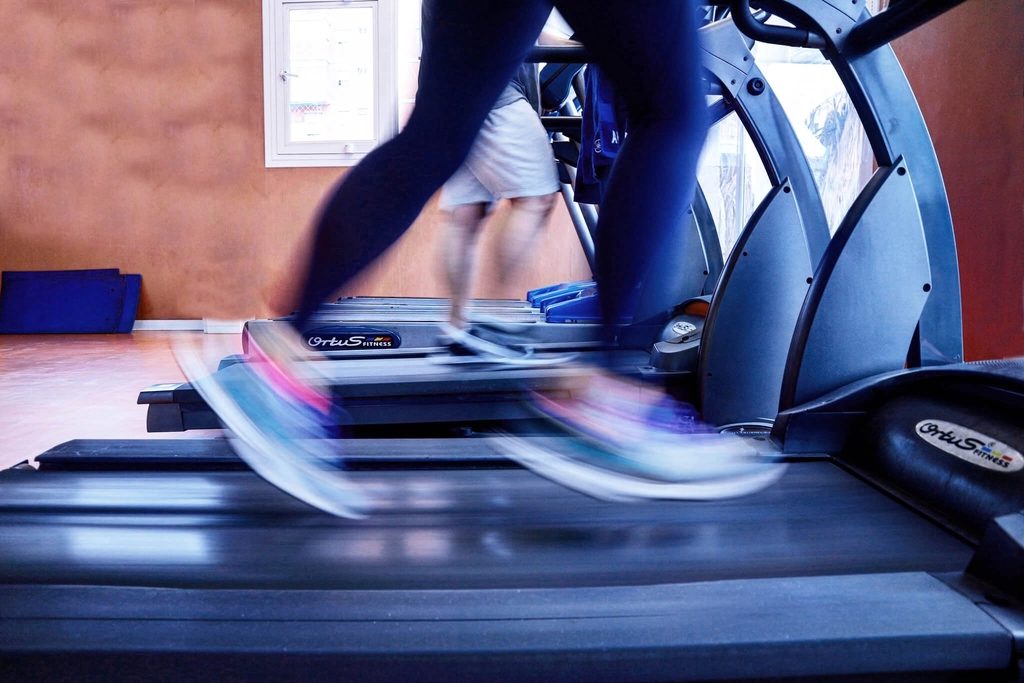 Runners on gym treadmills, their legs blurred with movement