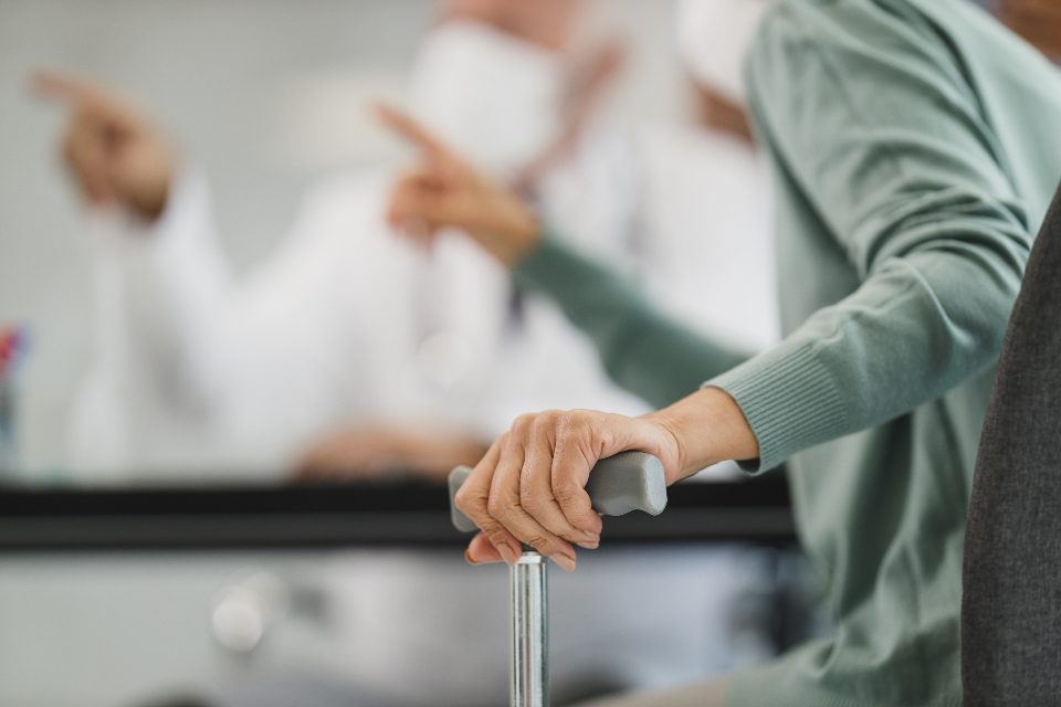 A hand resting on a walking stick handle while someone gives support